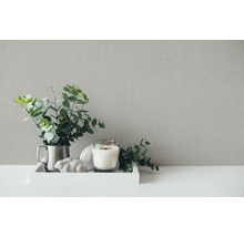 Dekorativt stilleben med texturerad bakgrund, bestående av ljus, prydnad och växt.