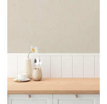 Miljöbild med beige non-woven tapet i linne-look ovanför en vit träpanelvägg