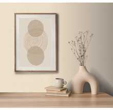 Dekorativ bild med cirkelmönster i träram, på ett bord med dekorativ vas och böcker