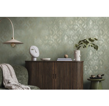 Dekorativt vardagsrum med byrå, lampa och tillbehör framför en mönstrad tapet