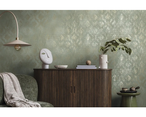 Dekorativt vardagsrum med byrå, lampa och tillbehör framför en mönstrad tapet