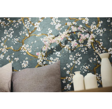 Närbild av en vägg med blommig tapet, kuddar och dekorativa vaser.