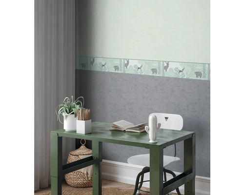 Dekorativt barnrum med skrivbord, stol och tapetbård med skogstema.