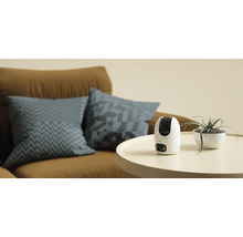 Imou övervakningskamera på ett bord bredvid en krukväxt och en soffa