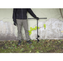 Person med jordborr i trädgården