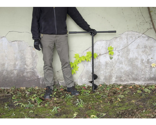 Person med jordborr i trädgården