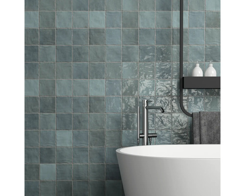 Modernt badrum med blåaktiga väggplattor, badkar och armatur.