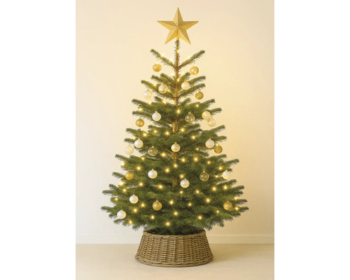 Dekorerad julgran med stjärna, kulor och ljusslinga i en flätad korg