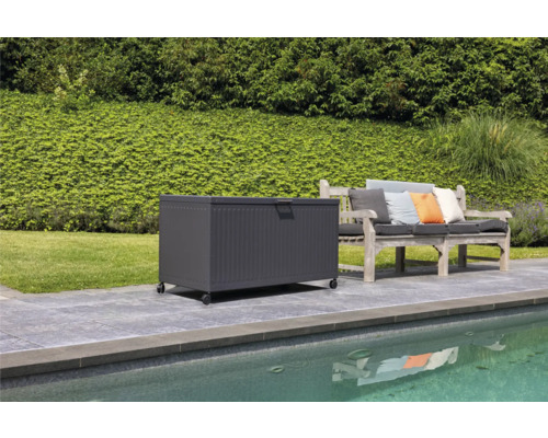 Scen med en förvaringslåda på hjul bredvid en trädgårdsbänk på en terrass vid en pool
