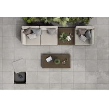 Översikt över en terrass med ljusgrå terrassplattor, loungemöbler och träbord