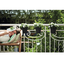 Kvinna kopplar av med en bok på en bänk på balkongen med blomlådor