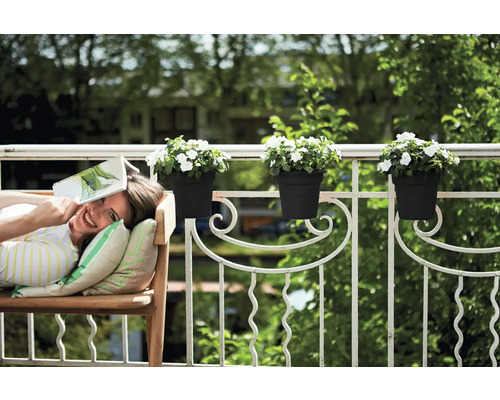 Kvinna kopplar av med en bok på en bänk på balkongen med blomlådor