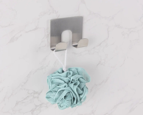 Duschsvamp hänger på en väggkrok i rostfritt stål