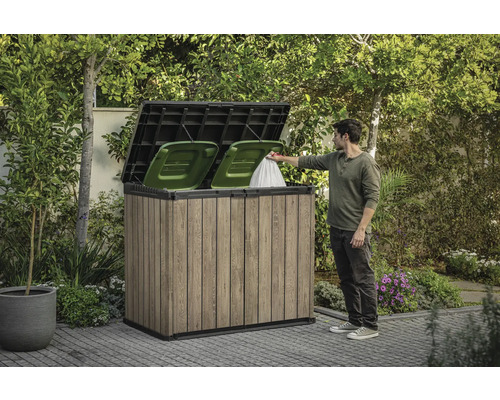 Soptunneskydd KETER Horizontal 1150l för 2x240L 141x82x120cm brun Soptunneskåp i trä med två gröna soptunnor och en person som kastar en soppåse i den