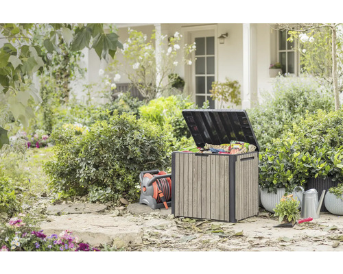 Utomhusträdgård med förvaringslåda, slangvinda, vattenkanna och växter