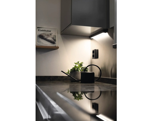 Köksscen med bänkskiva, krukväxt, vattenkanna, eluttag och köksbelysning