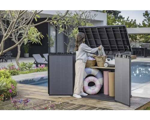 Bild på en kvinna som använder en förvaringslåda utomhus på en träaltan vid en pool för att förvara saker