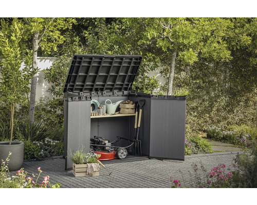 Trädgårdsskåp med öppna dörrar och uppfällt lock, fyllt med trädgårdsredskap och en gräsklippare