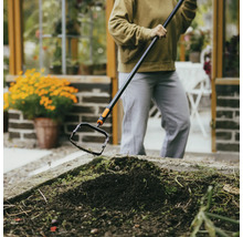 Person som tar bort ogräs med en oscilloskopisk hacka i en trädgårdsbädd.