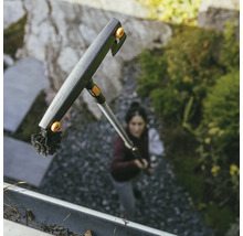 Takrännorrengörare med borste och teleskopskaft från Fiskars i bruk.