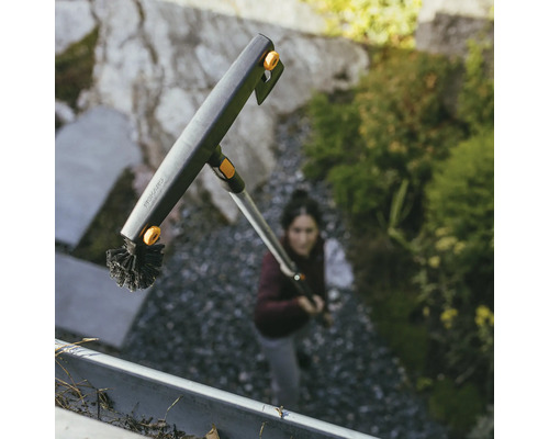 Takrännorrengörare med borste och teleskopskaft från Fiskars i bruk.