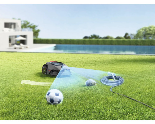 Robotgräsklippare på gräsmatta med fotboll, sten och trädgårdsslang
