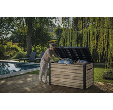 En kvinna öppnar en trädgårdskista på en träterrass bredvid en pool och trädgård.