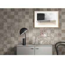 Väggdekoration med fyrkantiga plattor ovanför en skänk med lampa och dekoration