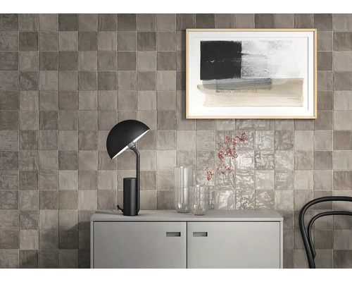 Väggdekoration med fyrkantiga plattor ovanför en skänk med lampa och dekoration