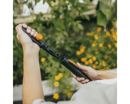 Två händer ansluter ett bevattningssystem från Fiskars.