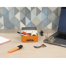 Skrivbordsscen med orange metallåda, kontorsmaterial och bärbar dator