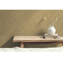 Dekorativ tapet med cirkelmönster på väggen ovanför en träbänk med böcker och en vas.