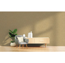 Vardagsrum med fåtölj, växt och byrå mot en strukturerad vägg