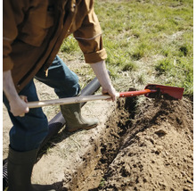 En person gräver ett dike i trädgården med en spade.