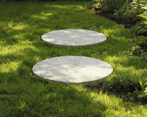 Två runda trampstenar av sten i gräsmattan