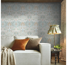 Vardagsrum med mönstrad tapet, soffa och golvlampa