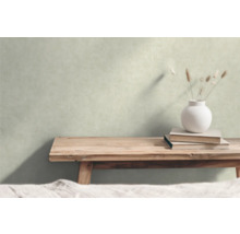 Dekorativ scen med en träbänk, böcker och en vas med gräs framför en vägg