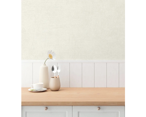 Scen med en ljusfärgad tapet, kombinerad med en bänkskiva i trä och köksredskap.