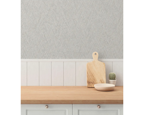 Dekorativ scen med en bänkskiva, en skärbräda i trä, en skål, en kaktus och en strukturerad tapet.