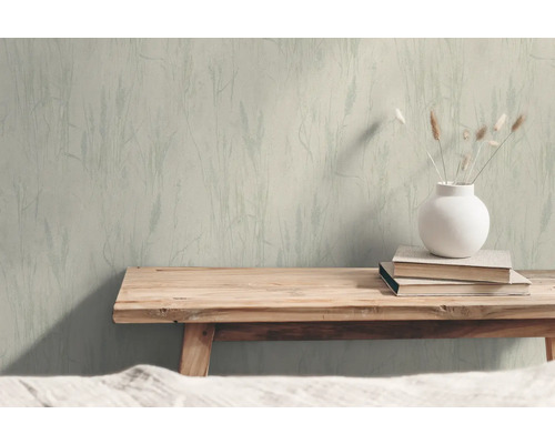 Vardagsrum med mönstrad tapet, sängbänk i trä, bok och vas