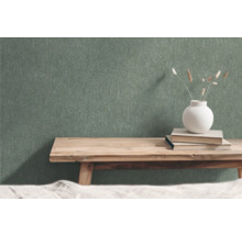 Grön non-woven tapet med strukturmönster i rum med träbänk, böcker och blomvas