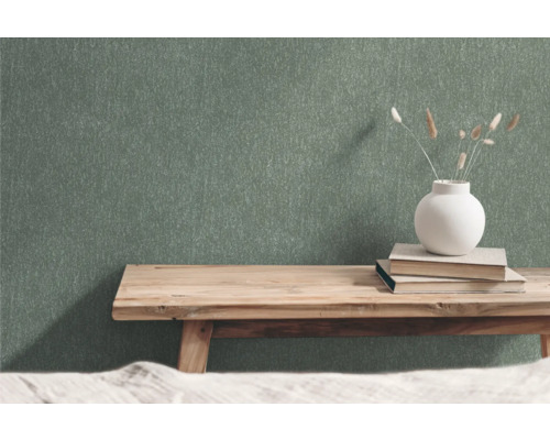 Grön non-woven tapet med strukturmönster i rum med träbänk, böcker och blomvas