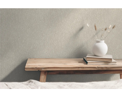 Närbild av en strukturtapet i en interiör med en träbänk, böcker och en blomvas som dekoration.