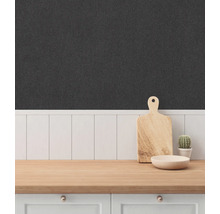 Detaljbild av ett kök med textiltapet, en bänkskiva i trä, en skärbräda och en växt.