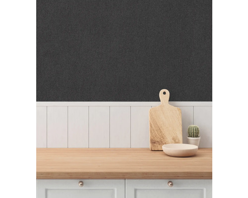 Detaljbild av ett kök med textiltapet, en bänkskiva i trä, en skärbräda och en växt.