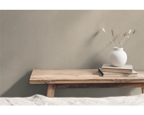 Träbänk med vas och böcker framför en vägg