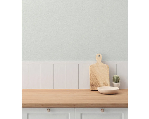 Köksscen med skärbräda, skål och kaktus på en träbänk framför en vägg med träpanel och tapet