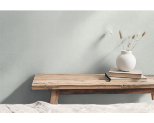 Dekorativ scen med en träbänk, böcker och en vas med prydnadsgräs