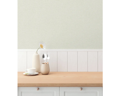 Ljus köksscen med mönstrad tapet, porslin och en blomma i en vas på en träbänkskiva.