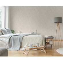 Sovrum med säng, sidobord, golvlampa och tapet med bladmönster